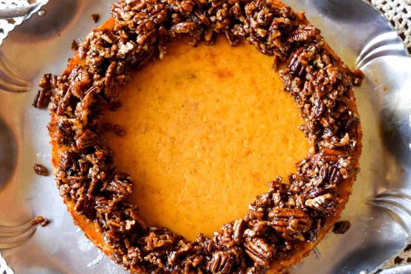 Pumpkin cheesecake with pecans on a silver plate.