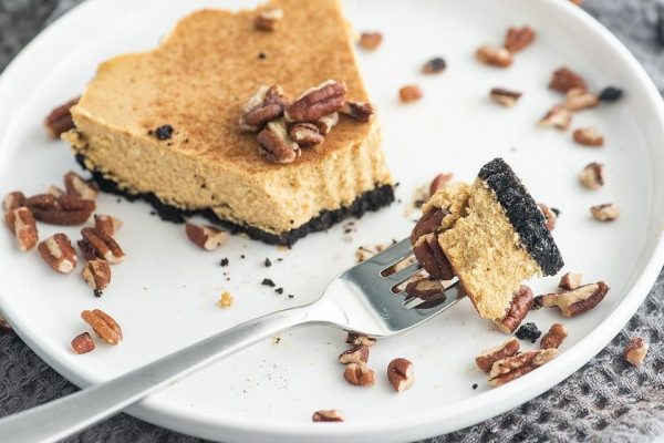 A slice of pumpkin cheesecake on a plate with a fork.