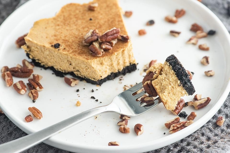 A slice of pumpkin cheesecake on a plate with a fork.