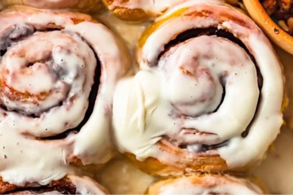 Cinnamon rolls with icing and nuts on a plate.