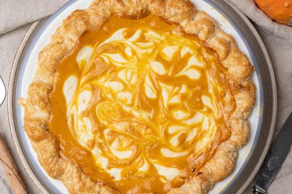 A pumpkin pie on a plate with a knife and fork.