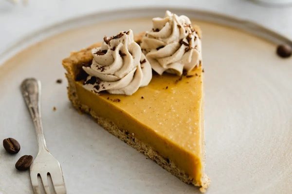 A slice of pumpkin pie on a plate with a fork.