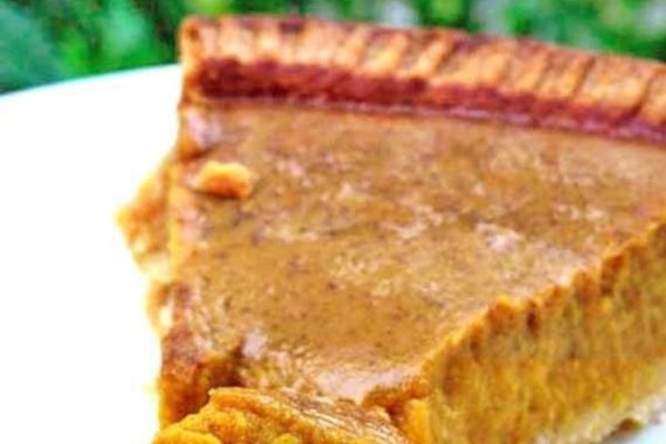 A slice of pumpkin pie on a white plate.