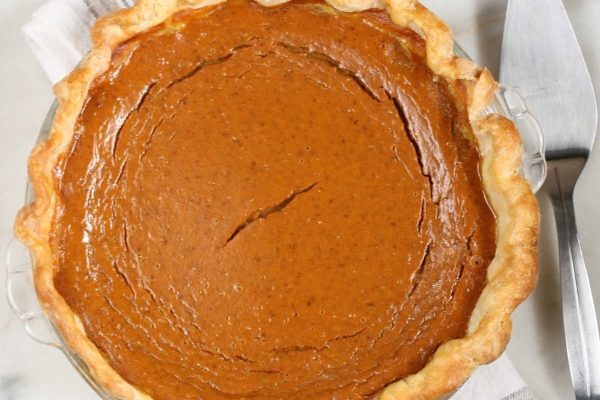 A pumpkin pie in a glass dish with a fork.