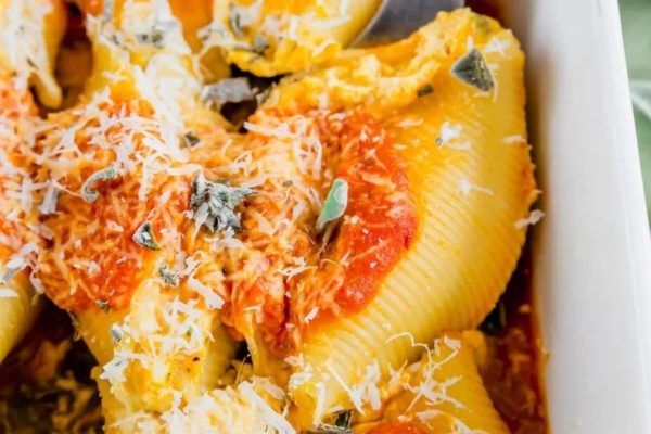 Stuffed shells in a white dish with a spoon.