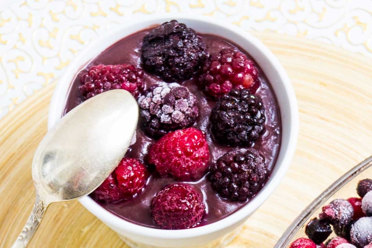 A delightful bowl of chocolate pudding with a handful of berries, perfectly accompanied by a shiny spoon. This indulgent treat is sure to please even the pickiest eaters with its rich and creamy
