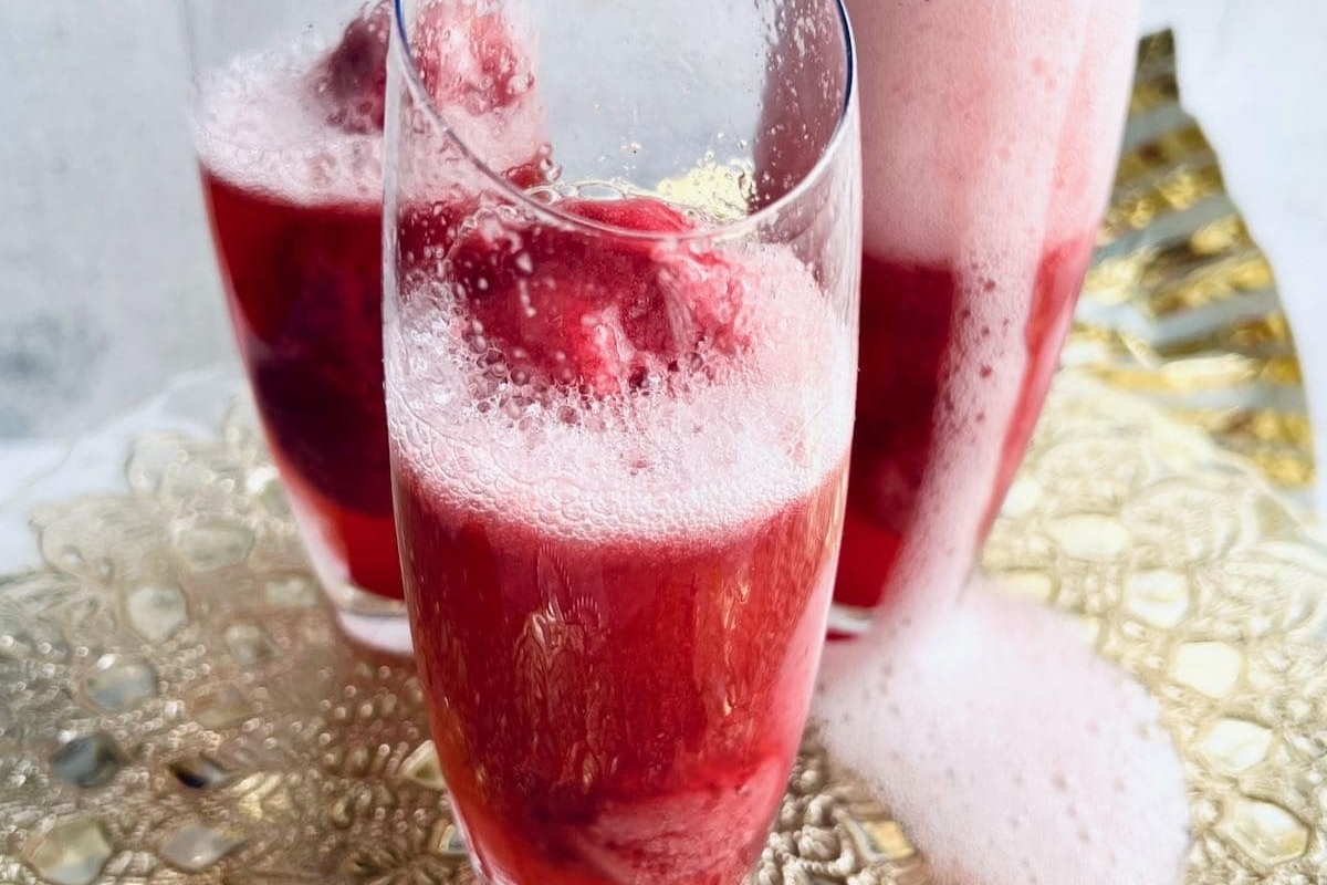 A glass of sparkling red wine with bubbles in it.