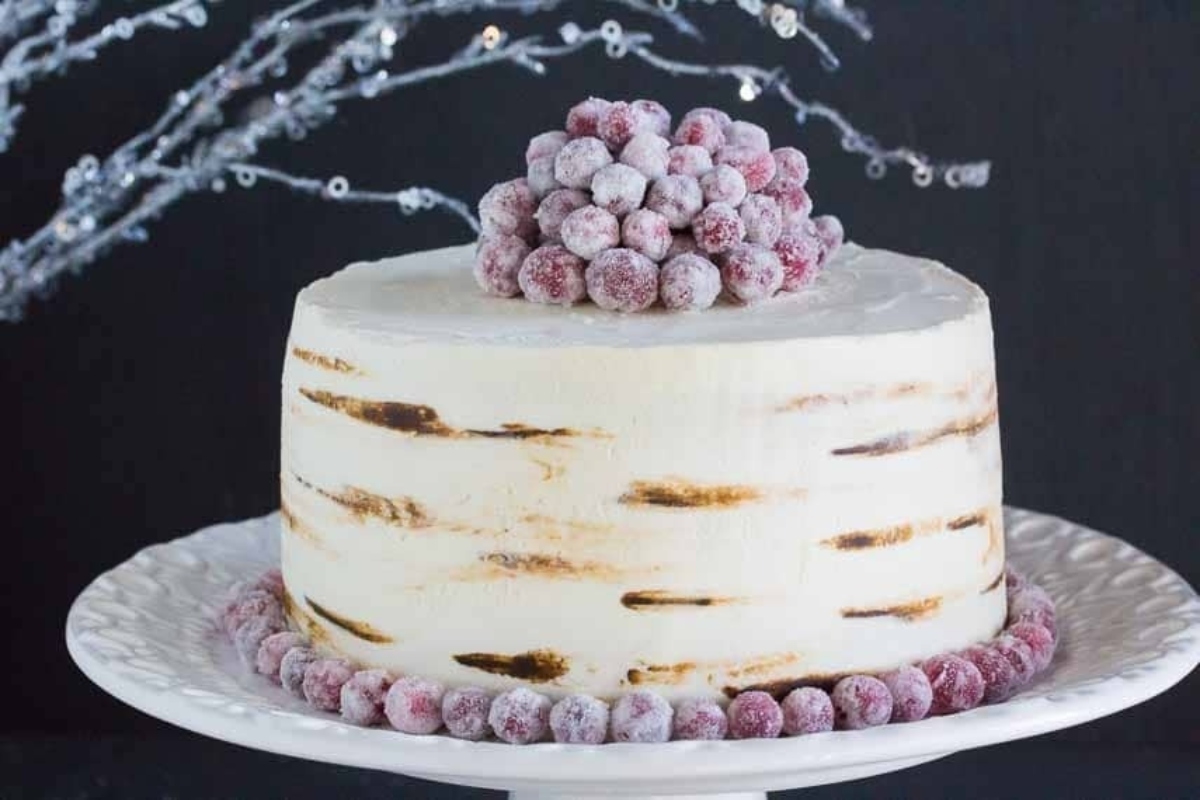 A white cake with Christmas berries on top.