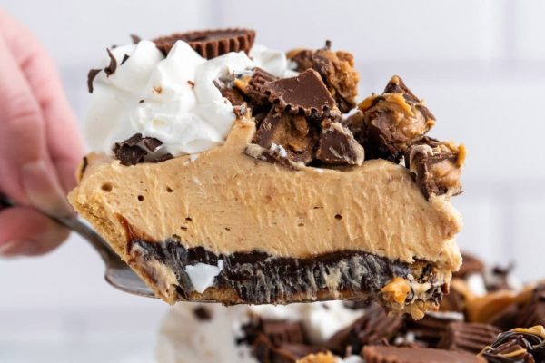 A person is holding a piece of peanut butter pie.