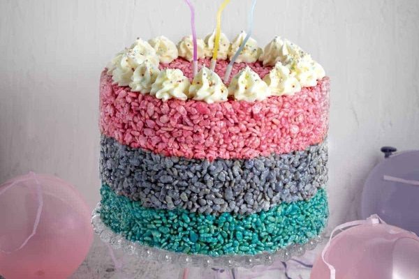 A pink, blue and purple layered cake with balloons.