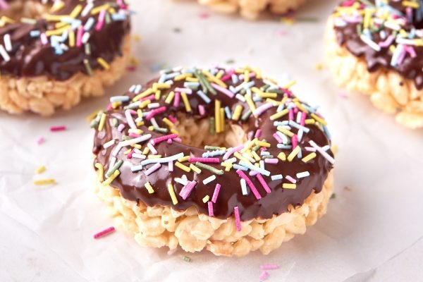 Chocolate covered rice krispy donuts with sprinkles.