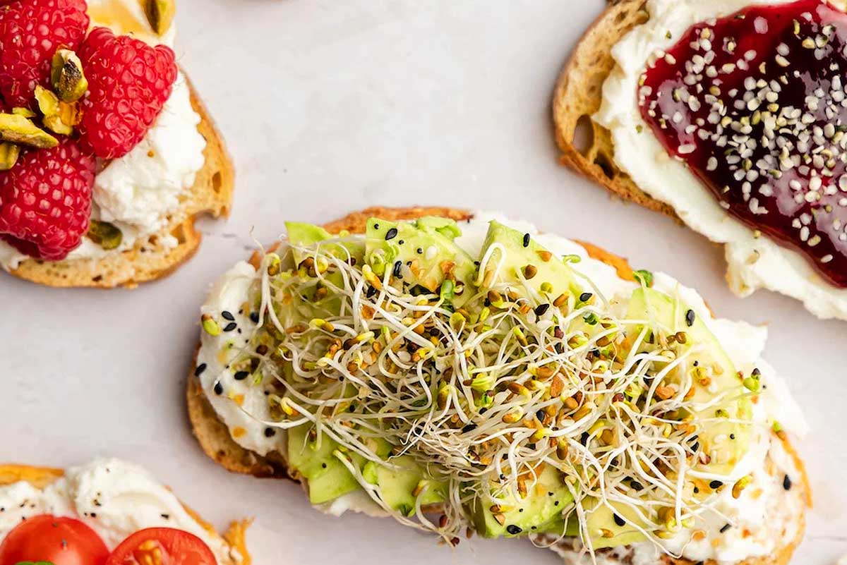 A plate of toasts with sprouts, strawberries and raspberries, perfect for a brunch gathering.