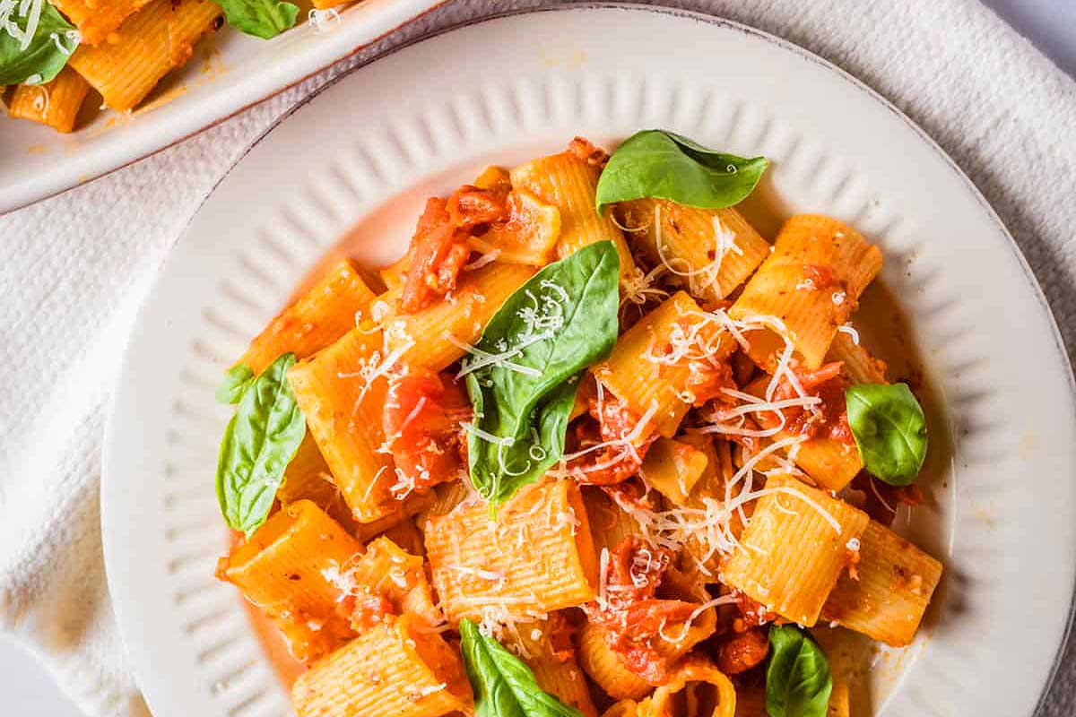 A romantic date night dish of pasta with tomatoes and basil elegantly presented on a white plate.
