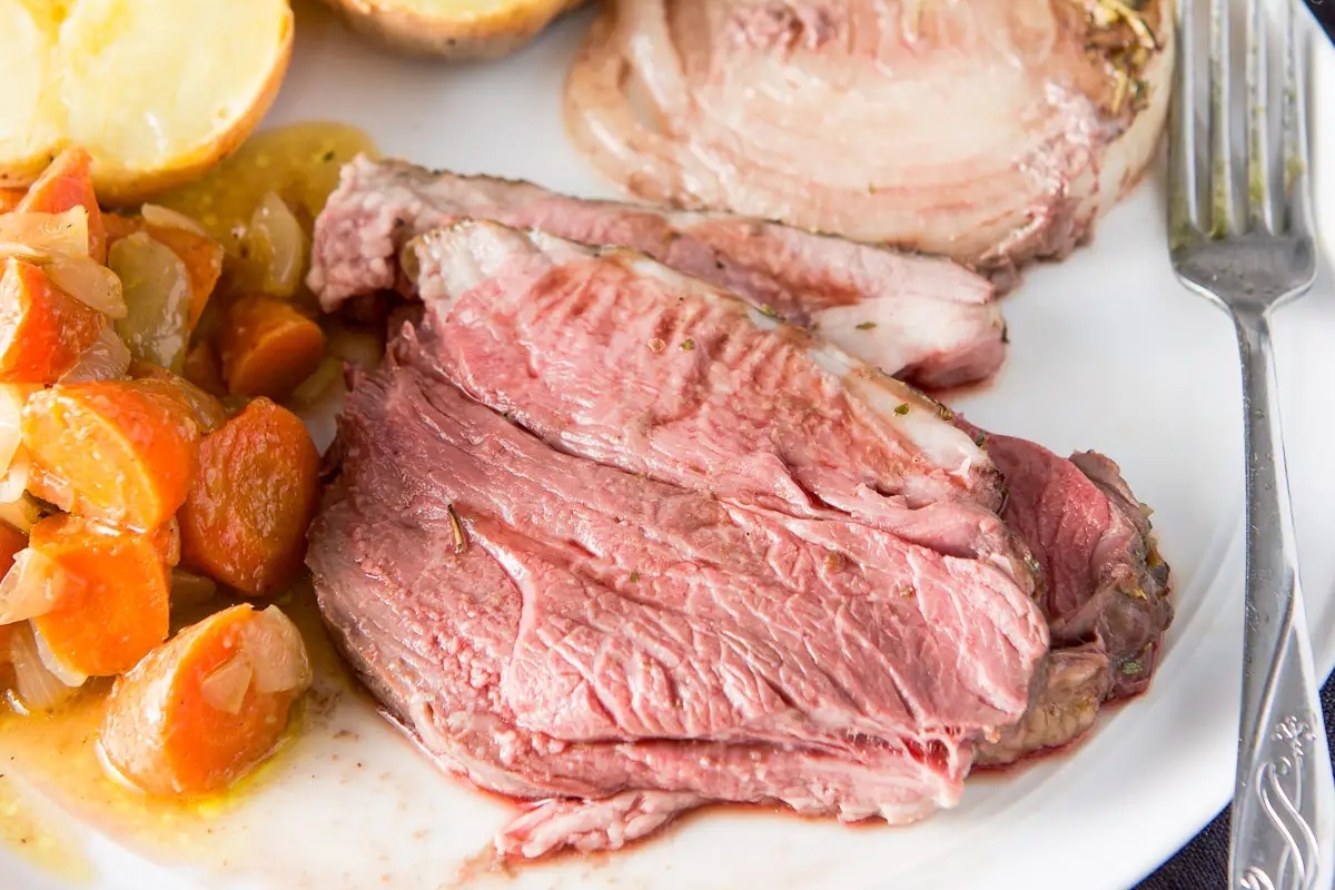 A hearty Thanksgiving main featuring roast beef with sides of carrots and potatoes.
