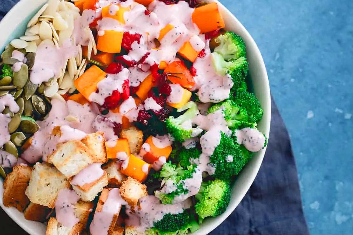 A bowl filled with broccoli, carrots and cranberries.