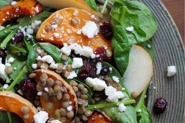 A plate of a salad with cranberries, spinach and feta.