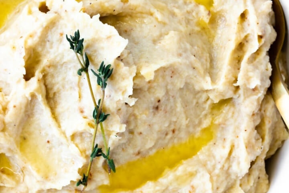 A country-style bowl of mashed potatoes with a sprig of thyme, perfect for Thanksgiving.