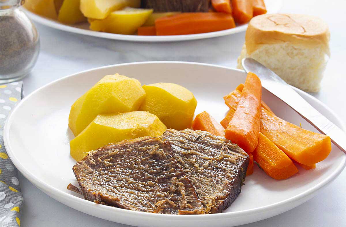 A plate of roast beef with carrots and potatoes.