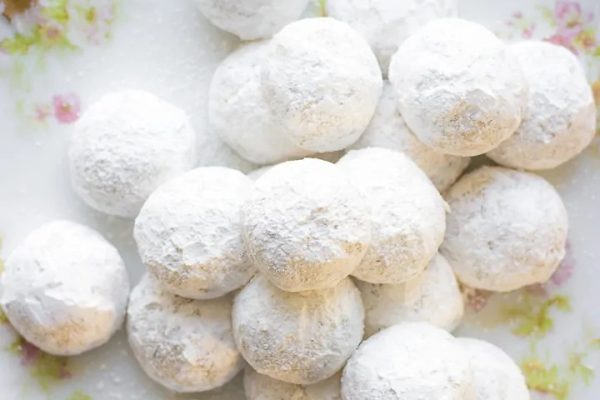 Traditional Christmas dessert of white powdered sugar balls on a plate.