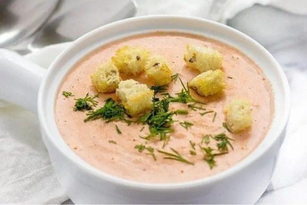A creamy soup with croutons and a spoon.