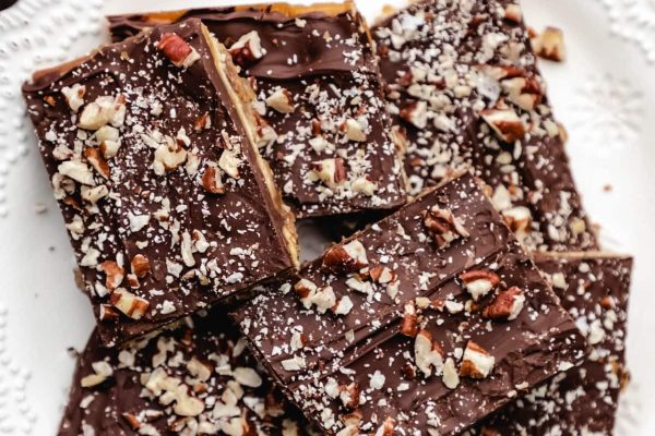 A plate of chocolate fudge topped with pecans.