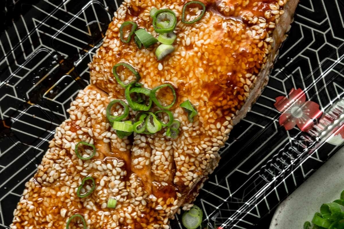 A stunning dinner party main featuring salmon adorned with sesame seeds and scallions, beautifully presented on a tray.