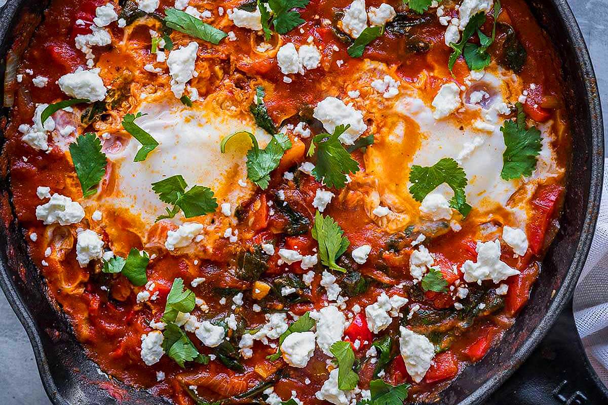 A skillet filled with eggs, tomatoes and herbs.