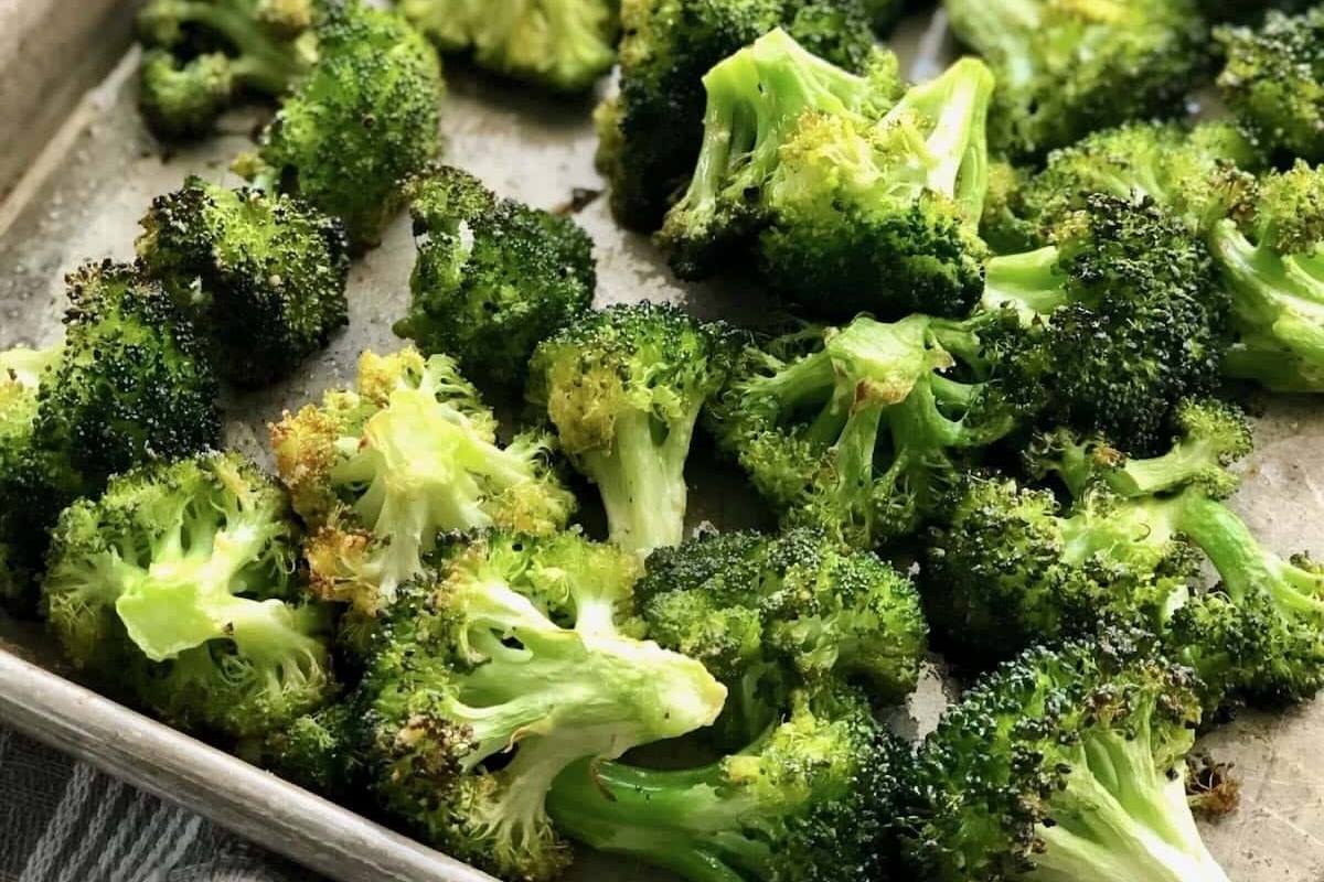 A sheet pan filled with roasted broccoli for a Thanksgiving feast.