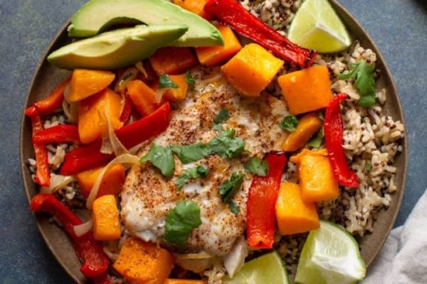 A plate of fish and vegetables with rice and avocado.