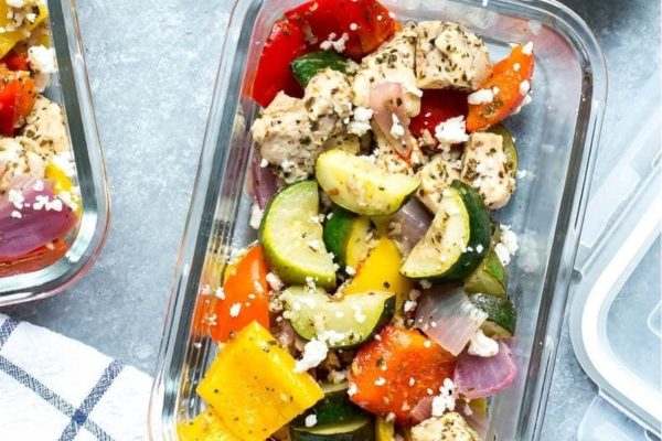 Three lunch containers with vegetables and chicken prepared for meal prep.