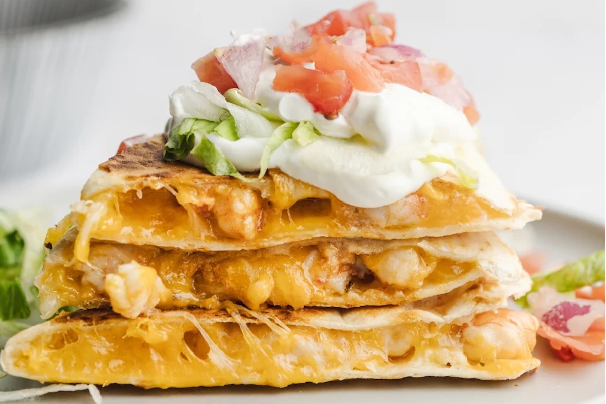 A stack of quesadillas with sour cream on top.