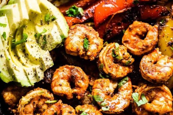 Shrimp in a skillet with avocado and tomatoes.