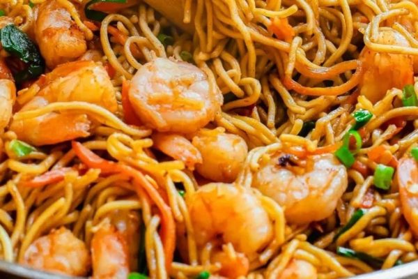 A pan full of noodles with shrimp and vegetables.