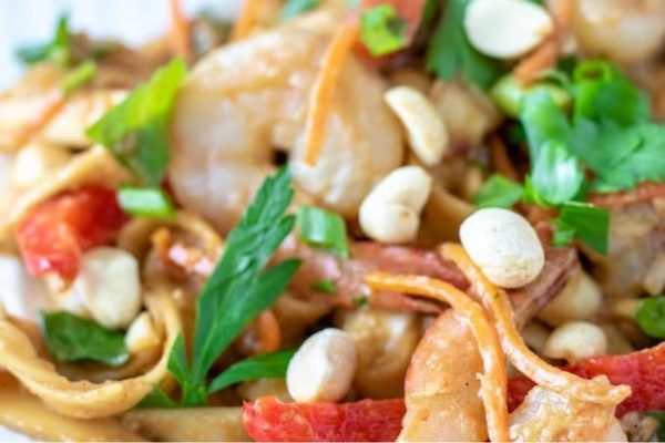 A plate of noodles with shrimp and peppers.