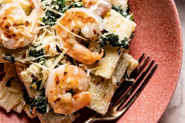 A plate of pasta with shrimp and kale.