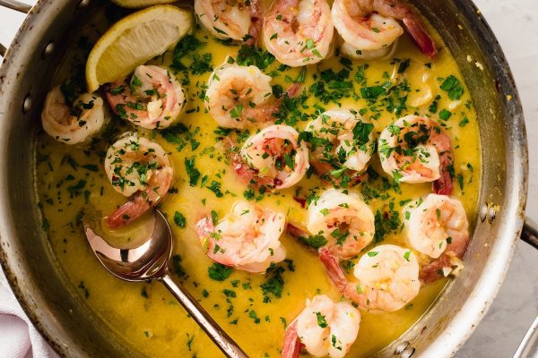Shrimp in a pan with lemon and parsley.