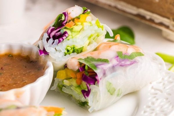 Vietnamese spring rolls on a plate with dipping sauce.