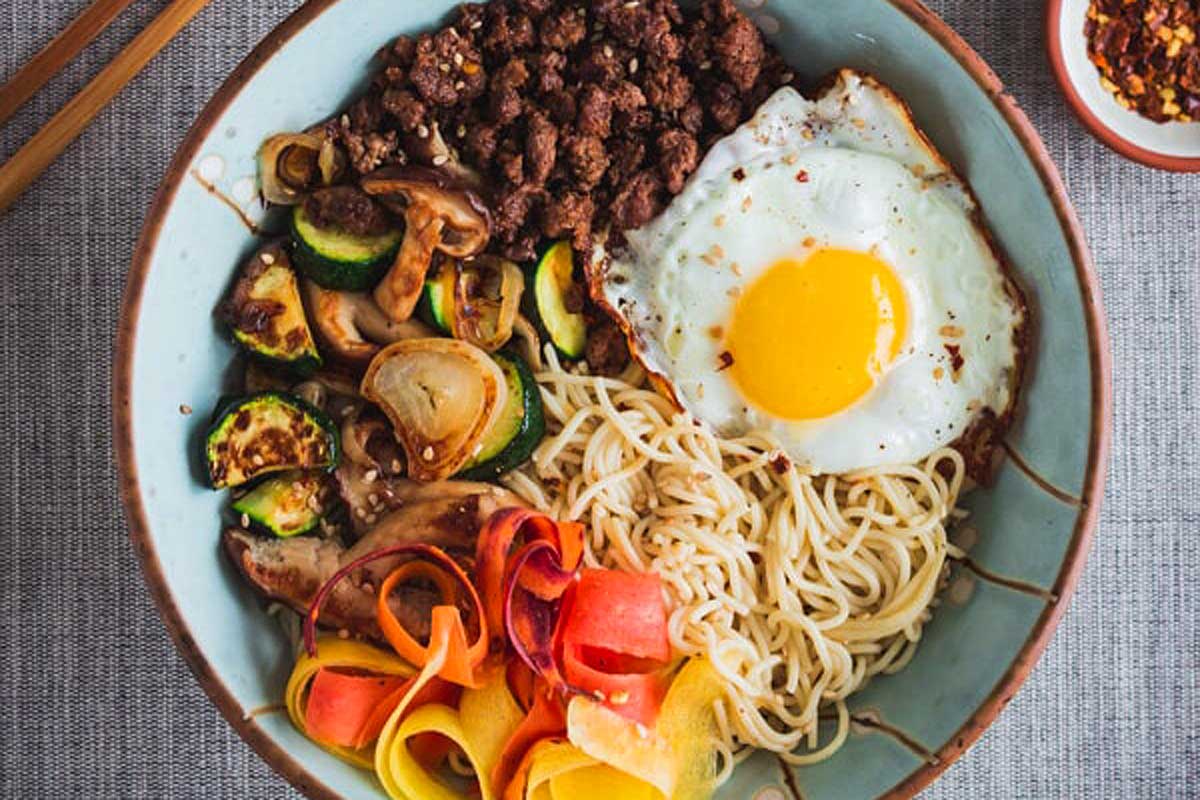 A bowl with noodles, vegetables and an egg.