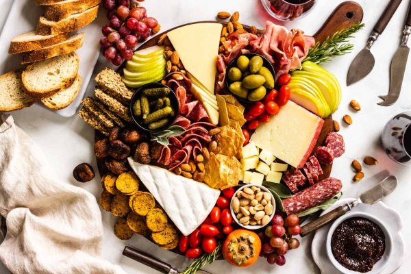 A festive charcuterie board filled with an assortment of meats, cheeses, and holiday delights displayed elegantly on a marble table.