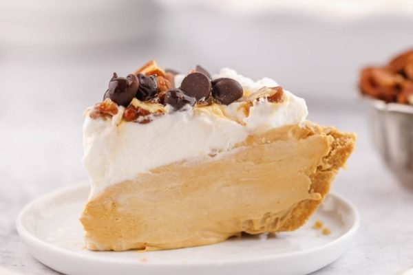 A slice of peanut butter pie with whipped cream and pecans.