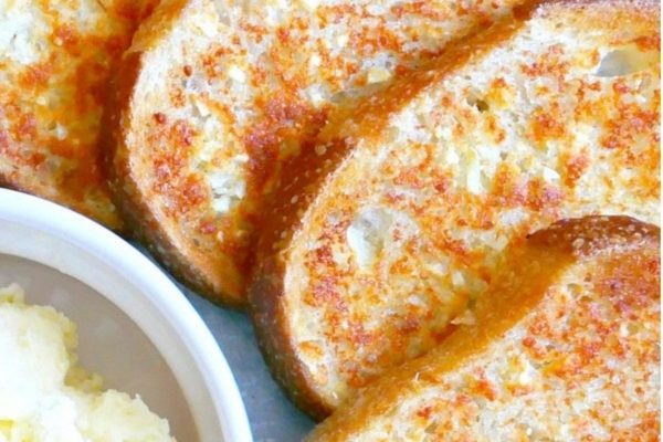 A plate of french toast with a bowl of butter.