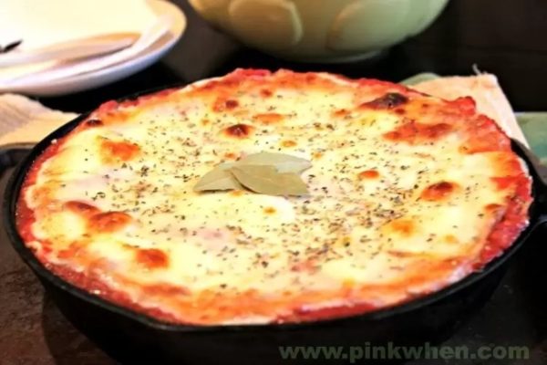 A pizza in a cast iron skillet on a table.