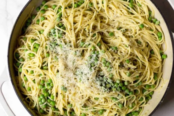A pan full of pasta with peas and parmesan.