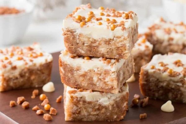 A stack of chocolate peanut butter bars on a wooden cutting board.