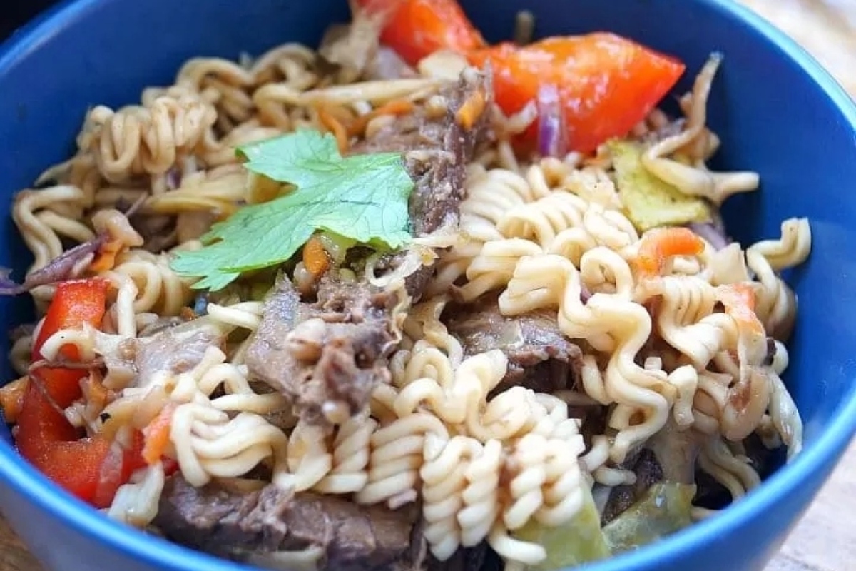 A bowl of noodles with meat and vegetables in it.