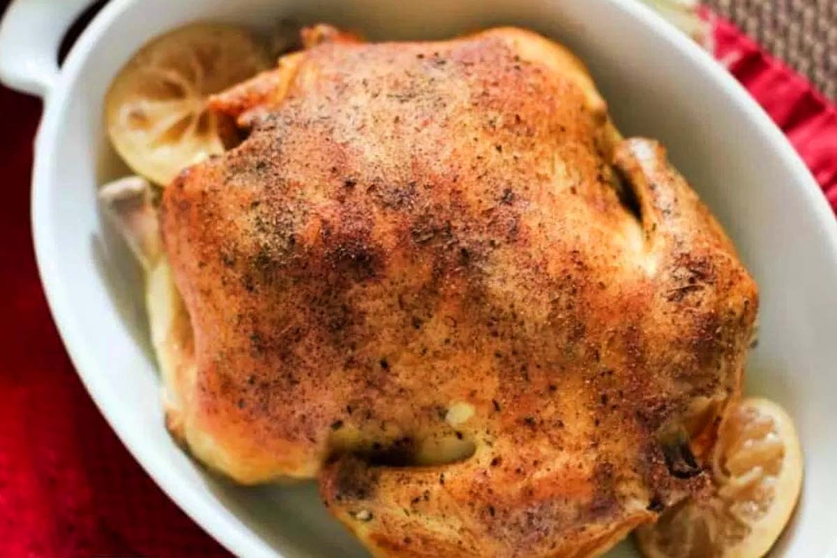 Slow Cooker Roasted chicken in a white dish with lemon slices.