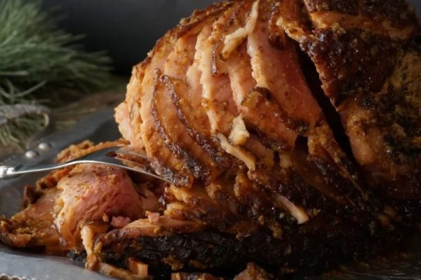 A roasted ham on a plate with a fork.