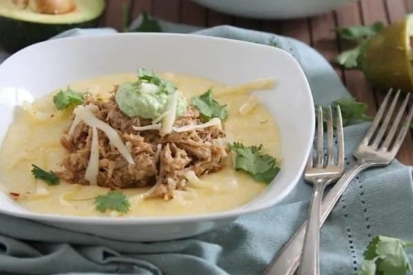 A bowl of chicken enchilada soup with guacamole and avocado.