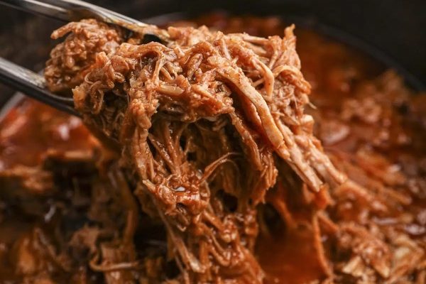 Slow cooker pulled pork with a fork.