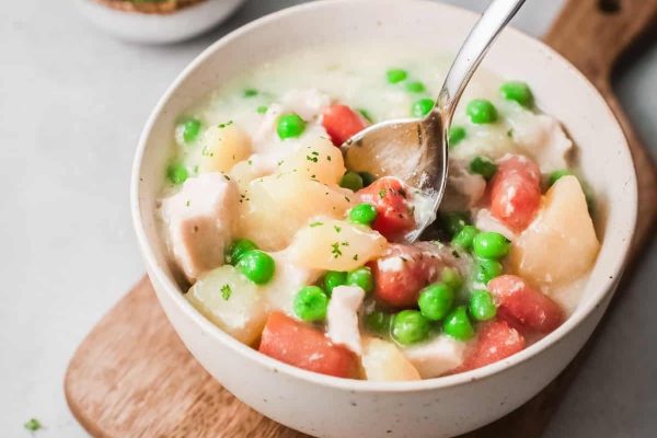 Chicken and pea soup in a white bowl with a spoon.